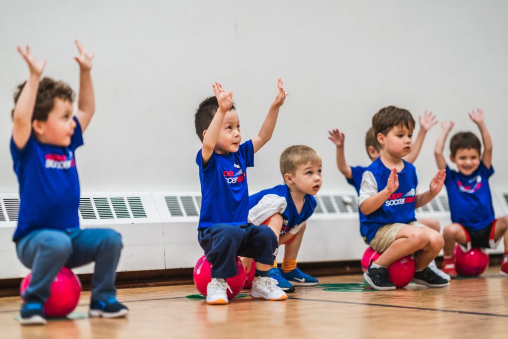 kids balancing on soccer balls celebrating