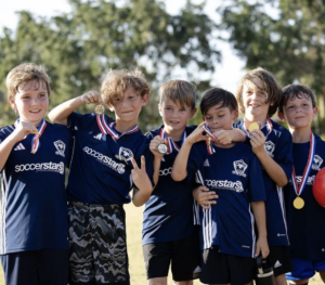 group of young boys holding up soccer medals